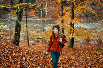 travel tourism woman in sweater and jeans in autumn forest near mountain river