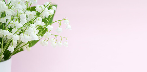 Fototapeta na wymiar lily of the valley flowers in a vase on a pink background.
