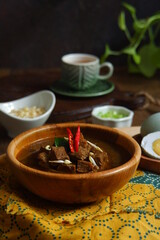 a bowl of black beef soup named rawon on the wooden table