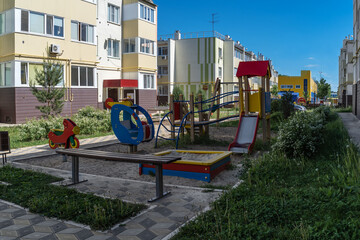 Cozy courtyard between houses with green plants and attractions for children. A wonderful space for outdoor recreation among conifers, shrubs and flowers