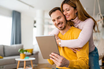Happy couple spending time with tablet at home