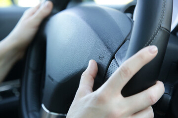 Woman hands on steering wheel pressing a horn