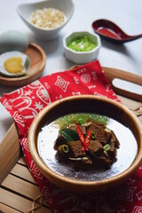 a bowl of black beef soup named rawon against white background 