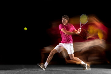 One man, male tennis player training isolated in mixed neon light on dark background. Concept of...