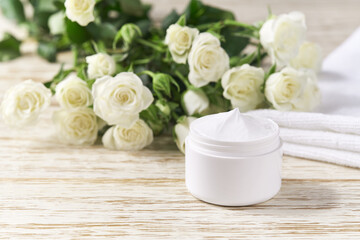 Fototapeta na wymiar Hygienic cream skincare product in white plastic jar with towel on wooden table.