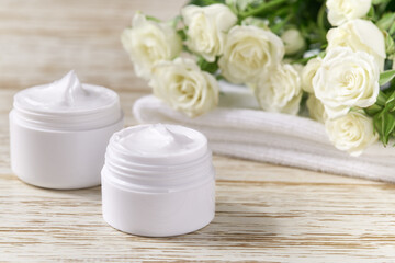 Fototapeta na wymiar Moisturizing cosmetic sensitive skin, hygiene skin care product or relaxing makeup mask in a white jar with a towel on a background of white roses.