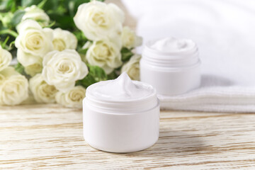 Obraz na płótnie Canvas Moisturizing cosmetic sensitive skin, hygiene skin care product or relaxing makeup mask in a white jar with a towel on a background of white roses.