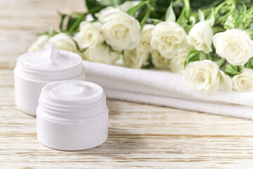 Fototapeta na wymiar Moisturizing cosmetic sensitive skin, hygiene skin care product or relaxing makeup mask in a white jar with a towel on a background of white roses.