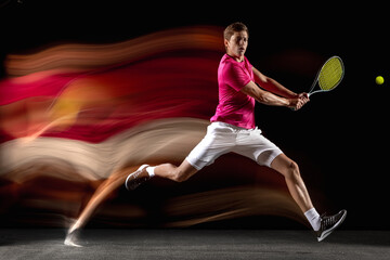 One man, male tennis player training isolated in mixed neon light on dark background. Concept of...