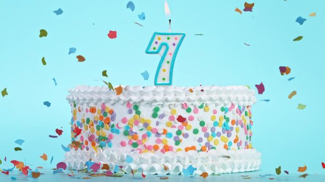 Birthday Cake With Burning Colorful Candle with Number 7 on Pastel Background. Falling confetti. Super Slow Motion, 1000 FPS.