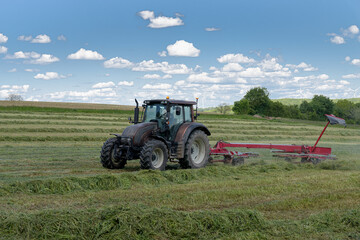 Fototapeta premium tracteur agricole rassemblant l'herbe sur le pré