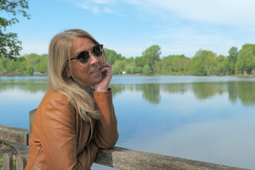Portrait of a woman with long blond hair in nature. Lake and vegetation blurred voluntarily in the background.