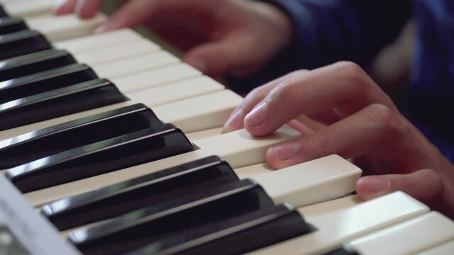 Close-up of fingers of a boy learning playing the piano.
