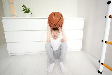 Little smiling schoolboy sitting on the floor at his white room