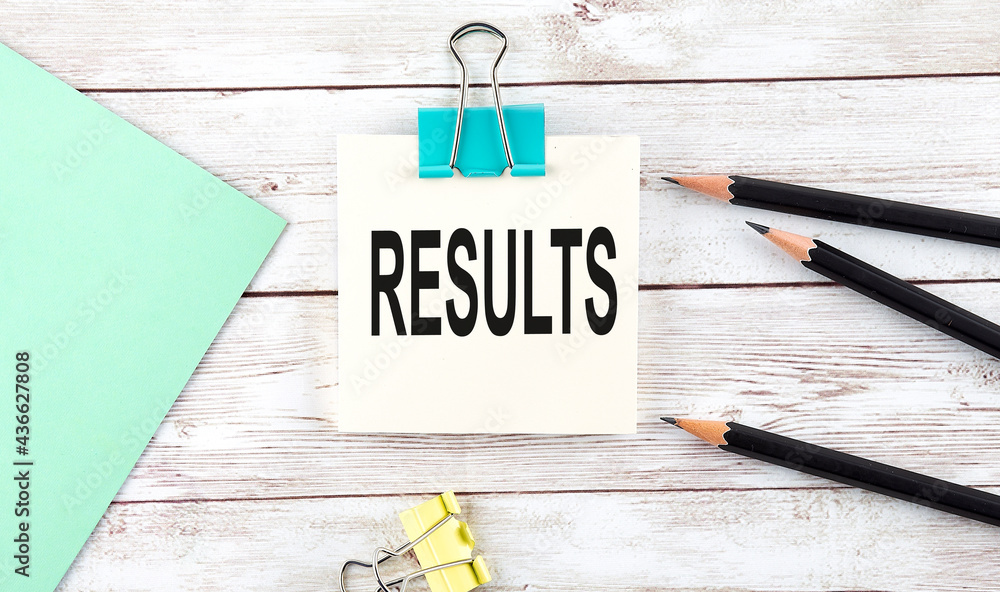 Poster stickers with pencils and notebook with text results on wooden background