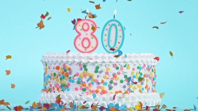 Birthday Cake With Burning Colorful Candles with Number 80 on Pastel Background. Falling confetti. Super Slow Motion, 1000 FPS.
