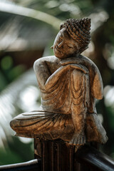 Statuette of Buddha on a background of green leaves close up. © grthirteen