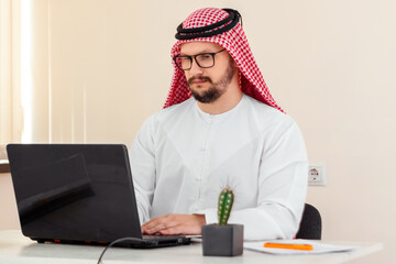 An Arab man, a businessman, a sheikh works at a laptop. Investments, business, work via the Internet, online contracts.