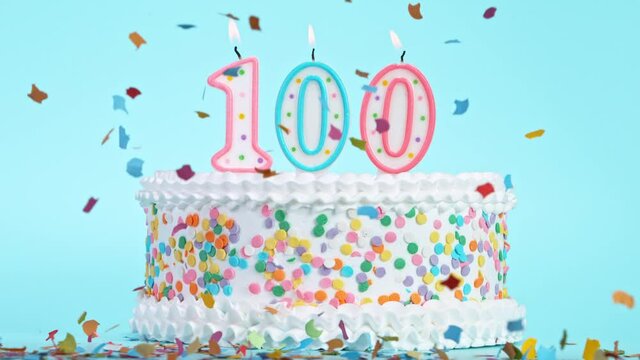Birthday Cake With Burning Colorful Candles with Number 100 on Pastel Background. Falling confetti. Super Slow Motion, 1000 FPS.