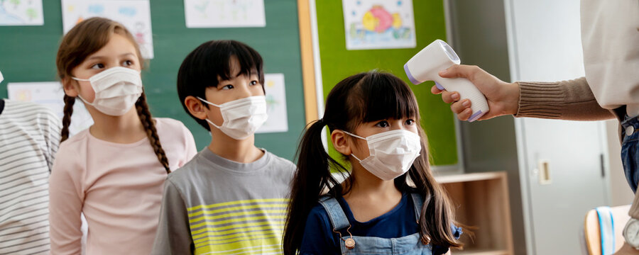 Banner of group of students in school building checked and scanned for temperature check. Elementary pupils wearing face mask and line up before entering into classroom. Covid-19 concept