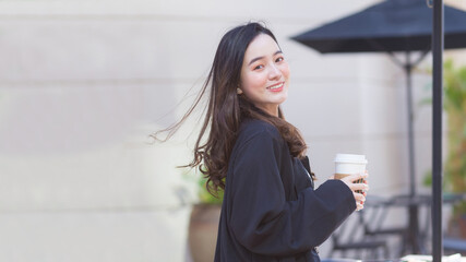 Asian beautiful woman in a dark blue suit is stand smile happy. In front of the coffee shop in the sunny morning © nut_foto