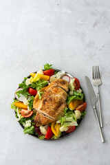 Delicious hearty lunch, chicken breast baked with spices and a mix of salad with tomatoes, radishes and cauliflower, top view, copy space