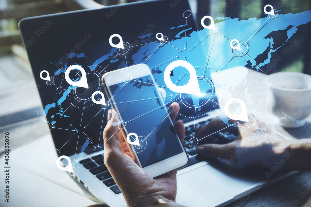 Aufkleber Geolocation and distributed data concept with hologram world map model and white pinpoints on man hands using cell phone and laptop backdrop