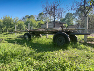 Trolley on wheels for transporting firewood, hay. Trolley on wheels in the village. Wooden carriage with logs.