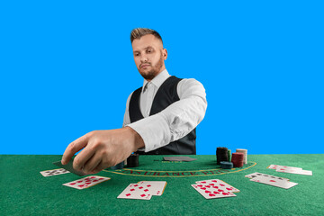 Male croupier at the casino at the table isolated on blue background. Casino concept, gambling, poker, chips on the green casino table. - obrazy, fototapety, plakaty