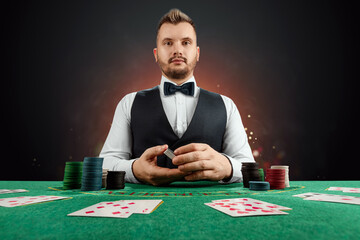 Male dealer at the casino at the table. Casino concept, gambling, poker, chips on the green casino table.