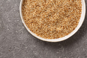 Sesame seeds in a bowl on a gray concrete background.