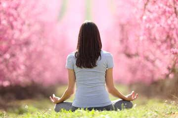 Back view of a woman doing yoga in a pink flowered field
