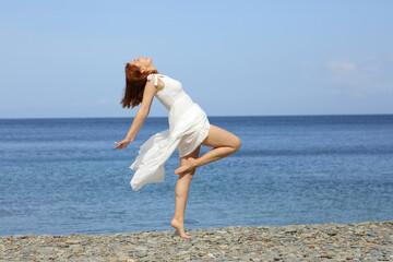 Fototapeta na wymiar Woman in white dress posing showing legs on the beach
