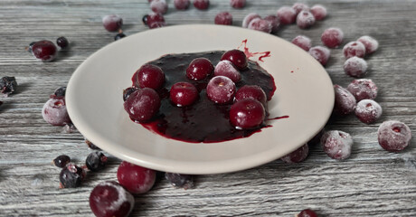 Berries background. Frozen berries, cherries, currants on a plate on a textured wooden surface. Fresh vitamins.