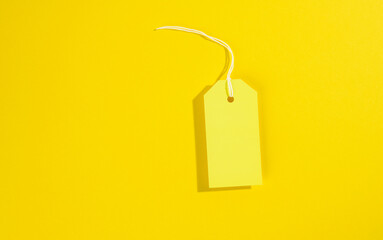 blank rectangular paper yellow price tag with white rope on yellow background