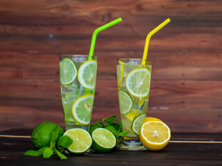 Front view shot of a glasses of homemade lemonade on wooden table with group of lemon, lime, and mint. There are two glasses of lemonade with copyspace on the side of image for texting for advertising