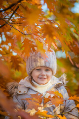 baby girl in autumn park playing with leaves