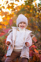 baby girl in autumn park playing with leaves
