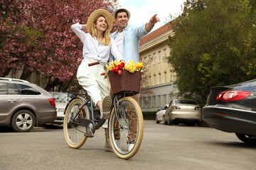 Lovely couple with bicycle and flowers on city street. Space for text