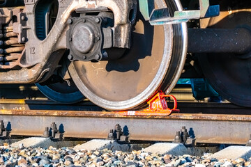 Fototapeta na wymiar railway brake shoe under the wheel of a railway carriage standing on a siding, awaiting cargo departure or waiting for an empty carriage to be loaded