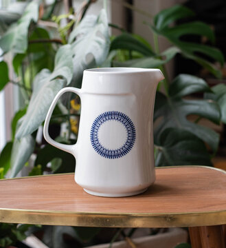 Mid-century modern design pitcher - water jug on a wooden table, in the background plants