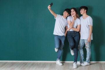 Company of Asian friends taking selfie in studio