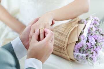 Obraz na płótnie Canvas Hand of The groom wears a wedding ring to the bride