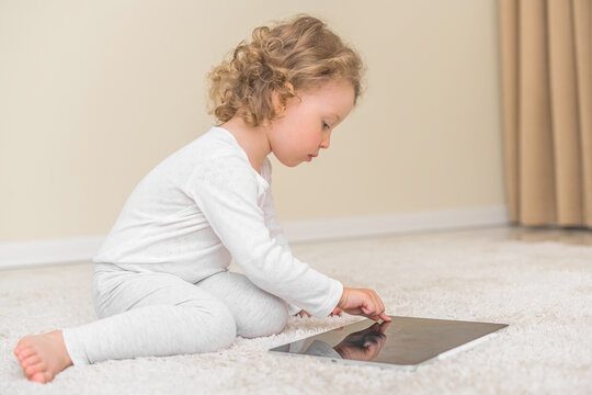 Little girl draws or plays on the tablet computer. Children and gadgets.