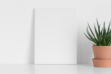 White canvas mockup with a cactus plant on the table.
