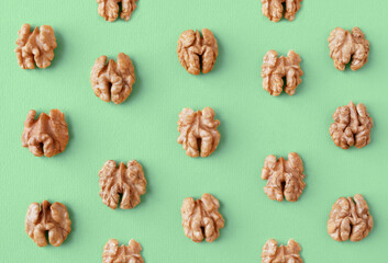 Halves of walnuts on a green trendy color 2021 year background, pattern, flat lay.
