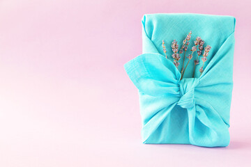 Aqua gift wrapping Japanese furoshiki style on pink background.