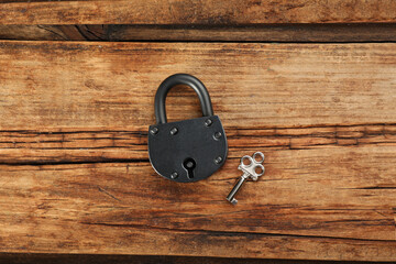 Vintage padlock with key on wooden table, flat lay