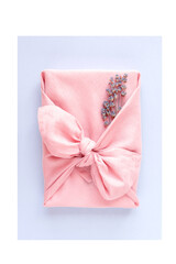 Pink gift wrapping Japanese furoshiki style on light blue background, flat lay.