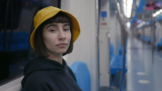 Woman in yellow bucket hat sitting at empty subway